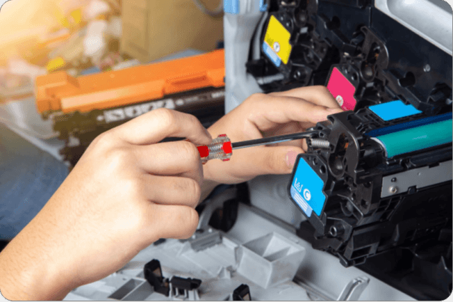 hand holding a screwdriver to fix a printer